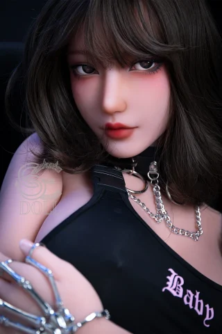 Makoto 157cm H Cup doll wearing a black outfit with silver chains, featuring long dark hair and soft makeup.