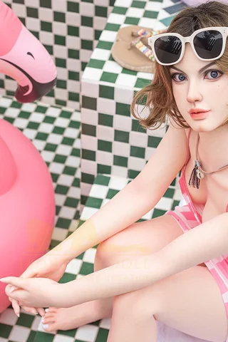 S9 163cm C Cup Irontech doll wearing a pink swimsuit, sitting beside a pink flamingo float in a tiled setting.