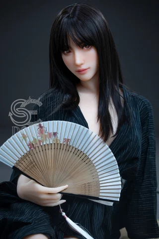 Aurora doll holding a fan, wearing a black robe with white stripes, featuring long dark hair and a neutral expression.