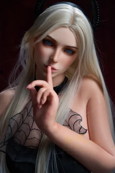 Figure with long blonde hair, finger to lips, wearing black outfit with lace detail and dark horns, resembling a B1 164cm Irontech Dark Tanned love doll.