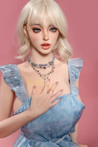 P1062714 doll features a light blue dress with ruffled sleeves, styled blonde hair, and a pearl necklace, against a pink background.
