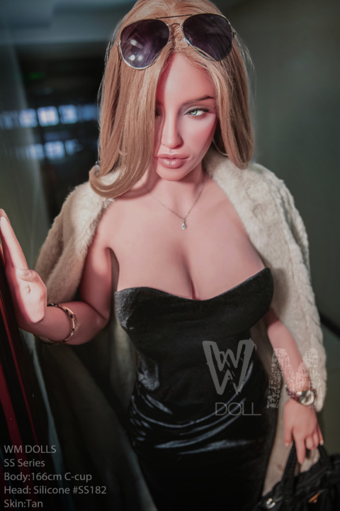 Rivian 166CM SS182 WM Doll in sunglasses, black dress, beige coat indoors.