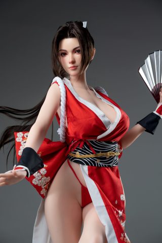 A fair-skinned doll with long dark hair, wearing a red kimono with floral patterns, poses gracefully while holding a fan.