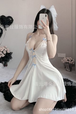 A model poses in a light blue lace nightdress with delicate bows, sitting on a plush surface surrounded by black heart balloons and flowers.