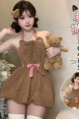 A model poses in a bear-themed short skirt dress made of fuzzy brown fabric, featuring bear ears and a pink bow, holding a teddy bear.