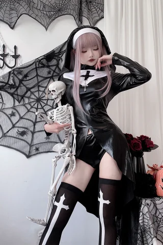 A figure in a black latex nun costume poses with a skeleton, featuring a short skirt and thigh-high stockings with cross patterns, against a backdrop of spiderwebs and Halloween decor.