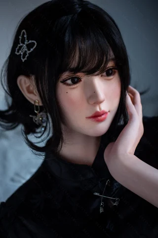 A close-up of a doll with short black hair, wearing a black cheongsam, adorned with a butterfly hairpin and earrings.