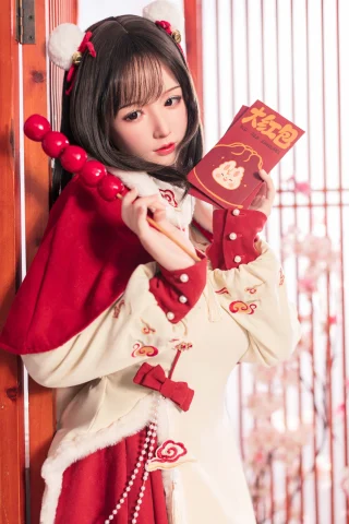A young woman in a festive outfit holds a red book and a decorative stick, set against a backdrop of wooden screens and cherry blossoms.