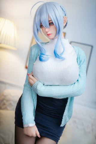 A doll with long, light blue hair stands in a softly lit room, wearing a white ribbed turtleneck and a light blue cardigan.