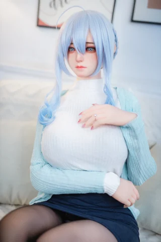 A doll with long blue hair sits on a couch, wearing a white sweater and a light blue cardigan, with a soft expression.