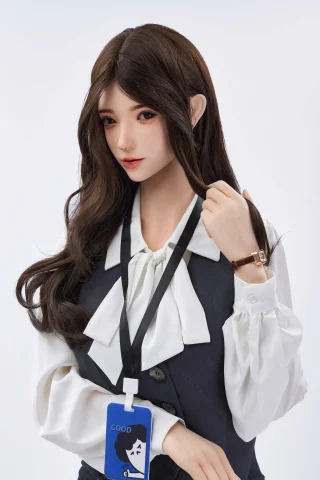 A doll with long, dark hair styled elegantly, wearing a white blouse with a bow tie and a dark vest, holding a strand of hair.