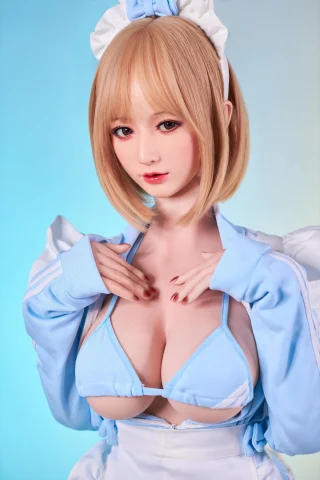 A doll with short blonde hair and a blue outfit, featuring a low-cut top and white accents, poses with hands near her chest against a soft gradient background.