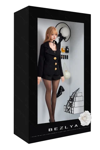A doll in a black blazer and shorts stands inside a display box, surrounded by modern decor items like a lamp and books.