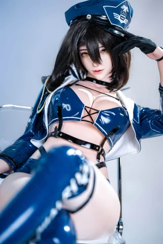 Subject in a shiny blue outfit with a police theme, featuring a cropped jacket, thigh-high boots, and a cap. The pose is confident, with a playful expression.
