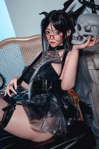 Subject: Doll in a gothic outfit with a sheer black dress, glasses, and long hair, holding a skull, posed on a vintage chair.