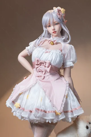 Doll in a pastel pink and white dress with ruffled sleeves, adorned with stars and a large bow, set against a soft, neutral background.