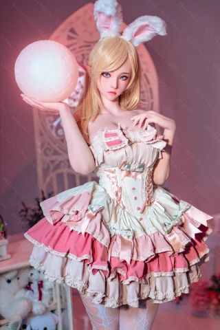 Dressed in a pastel-colored, frilly dress with pink and cream hues, holding a large white orb, and featuring bunny ears.