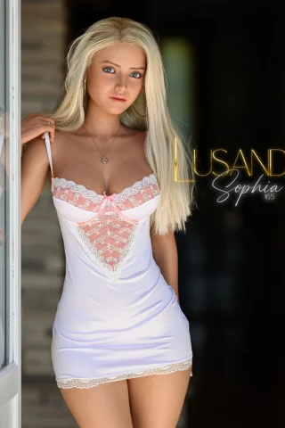 Sophia 165cm Lusandy in a light pink nightgown with lace trim, standing in a doorway, framed by wooden panels.