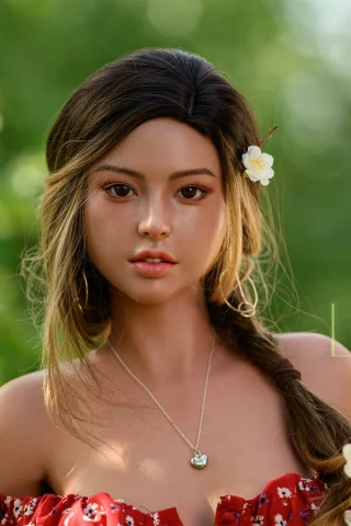 Naomi B Cup 167cm Lusandy Silicone features a floral dress, long braided hair, and a delicate necklace, set against a lush green background.