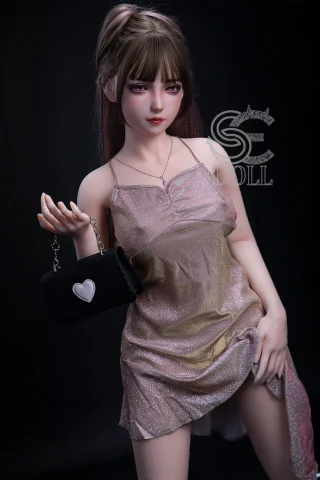 A doll with long, straight hair styled in a ponytail, wearing a shimmering, pastel-colored dress, holds a small black purse with a heart charm.