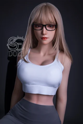 A doll with long blonde hair and glasses wears a white crop top and gray leggings, posed against a dark background.