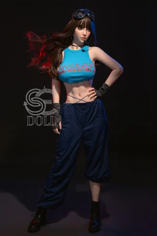 A doll with long dark hair wearing a blue crop top and loose navy pants, accessorized with goggles and black boots, stands confidently.