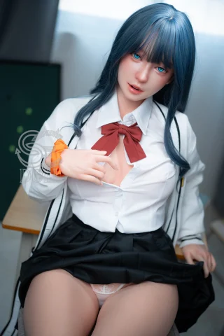 A doll with long blue hair and striking blue eyes wears a white shirt with a red bow tie and a black skirt, sitting on a desk.