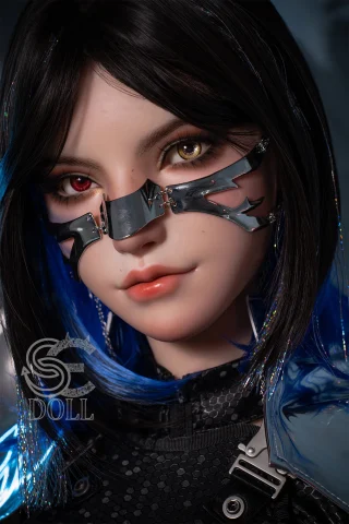 The image features a close-up of a doll with striking dual-colored eyes, one red and one yellow. The doll has sleek black hair with vibrant blue highlights and wears a futuristic outfit. A metallic face mask with angular designs covers part of the face, adding an edgy look. The background is softly blurred, enhancing the doll's detailed features.