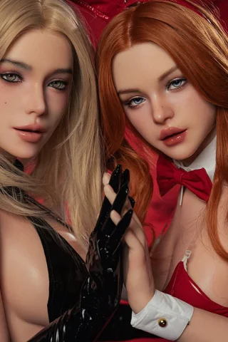 Two realistic dolls from SE Doll, one with blonde hair in black attire and the other with red hair in a red outfit.