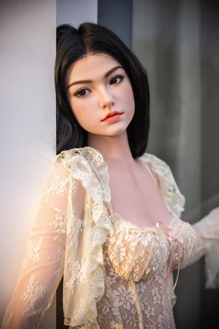 Qingwen 163cm C-Cup Starpery doll in a lace outfit with ruffled sleeves, standing against a wall.